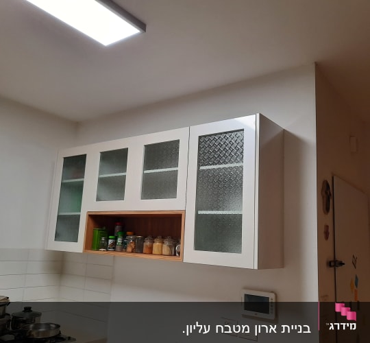 ארונות מטבח עם דלתות זכוכית ותבלינים על מדף